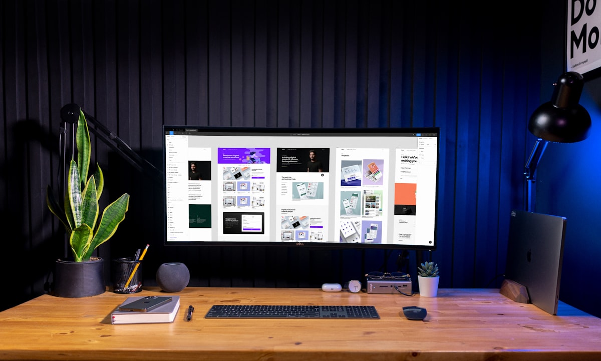 A designer's workspace with a large monitor showing a portfolio of design work
